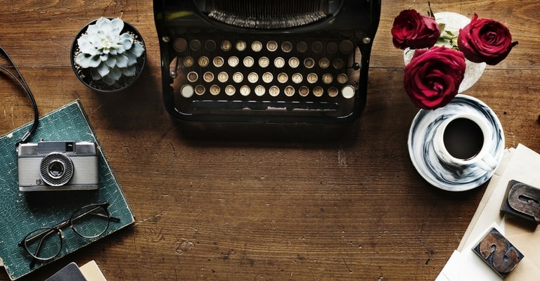 Machine à écrire, appareil photo, roses et café sur table