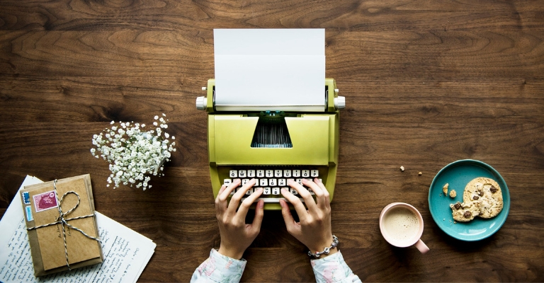 Machine à écrire verte, café, cookie et fleurs